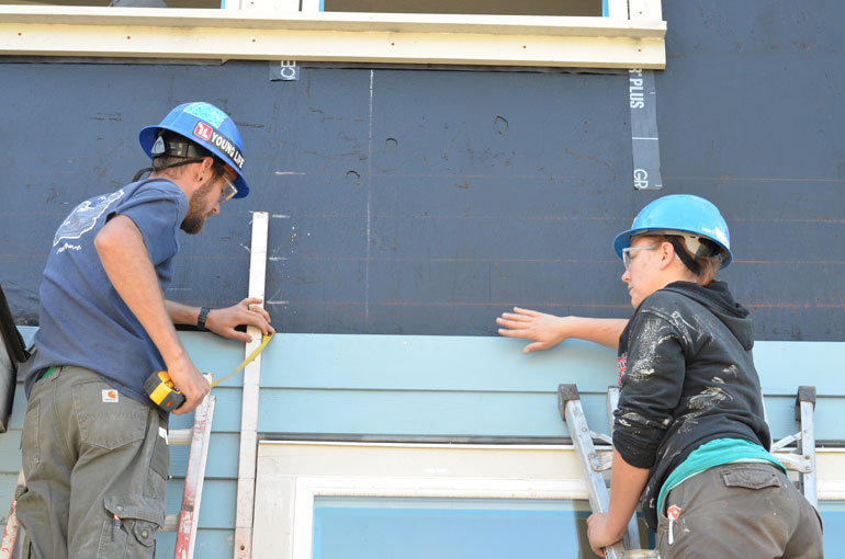 Americorps members work on a siding project.